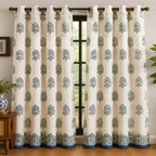 White curtain with blue floral pattern in a room with wooden floor and plant.