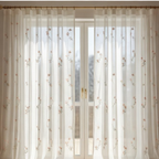 Sheer white curtain with floral patterns in front of a window