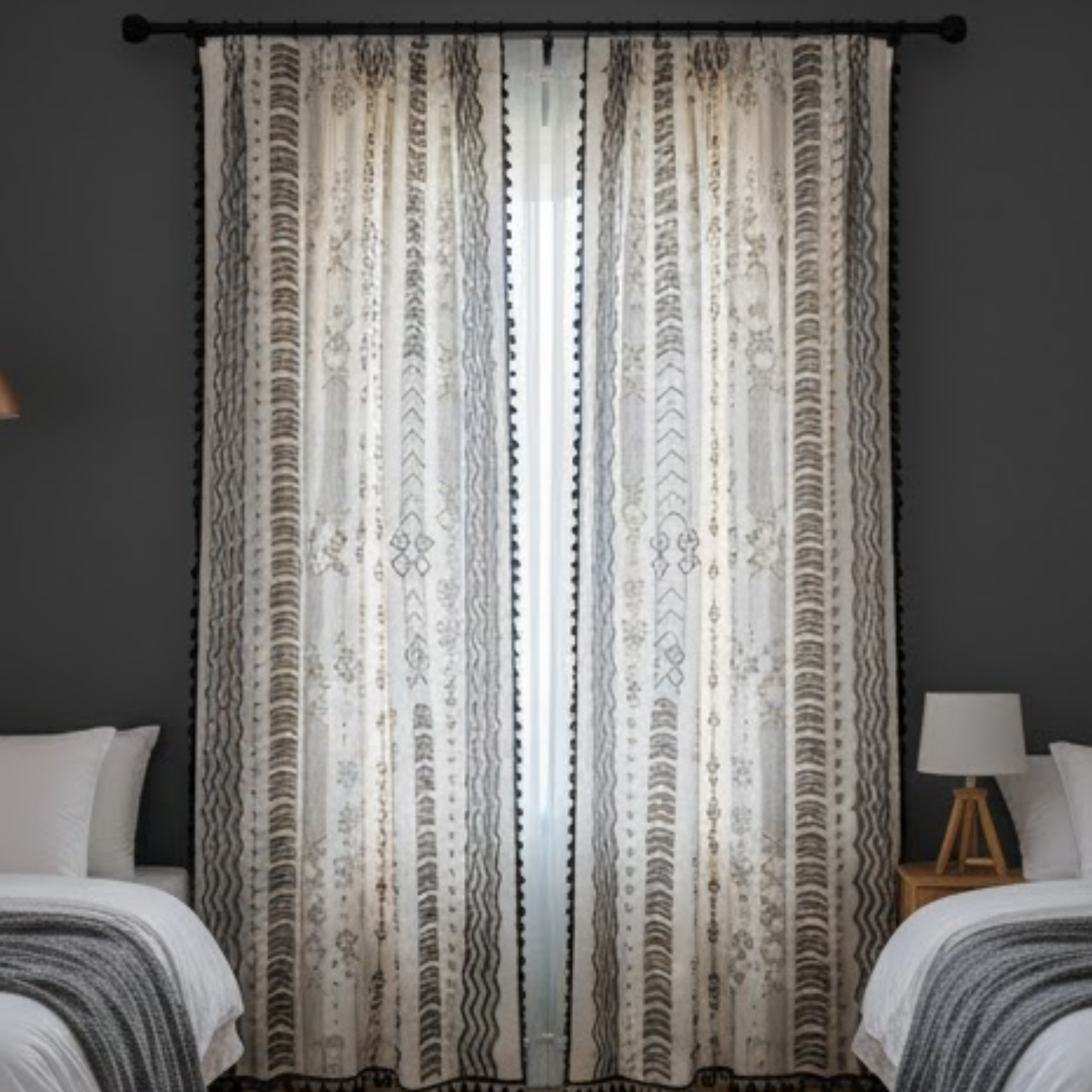 Patterned curtains in a bedroom setting with dark walls and bedding.