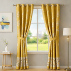 Yellow floral curtains hanging in a room with a window, side table, and lamp.